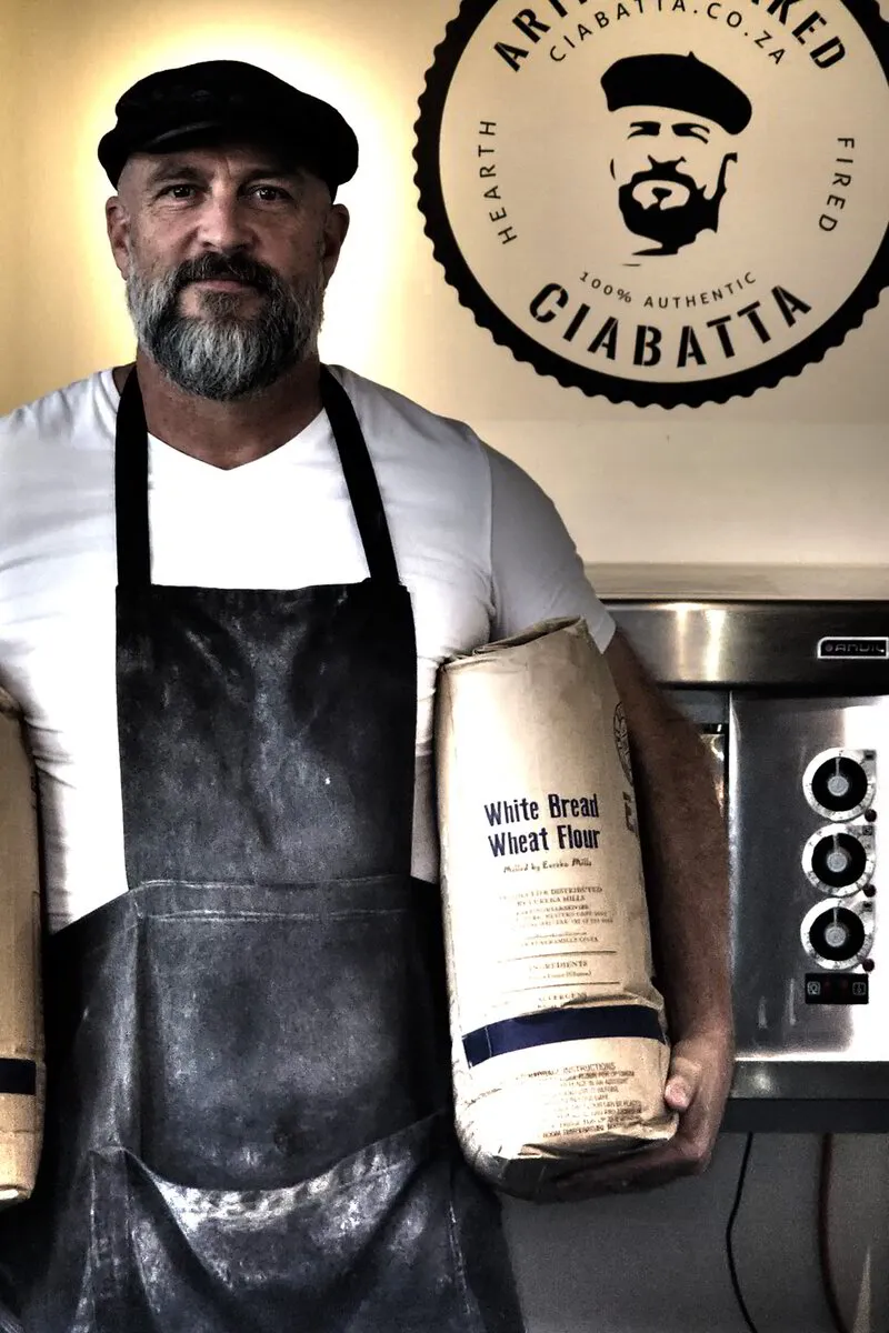John the Baker in his bakery with bags of flour